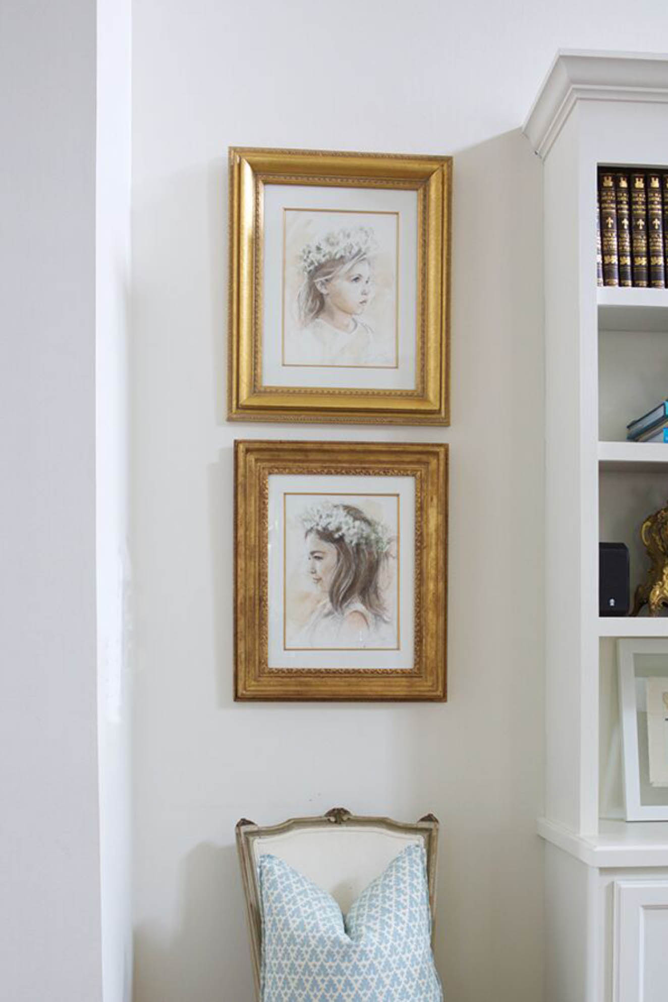 Two drawn portraits of little girls with flower crowns in gold frames.