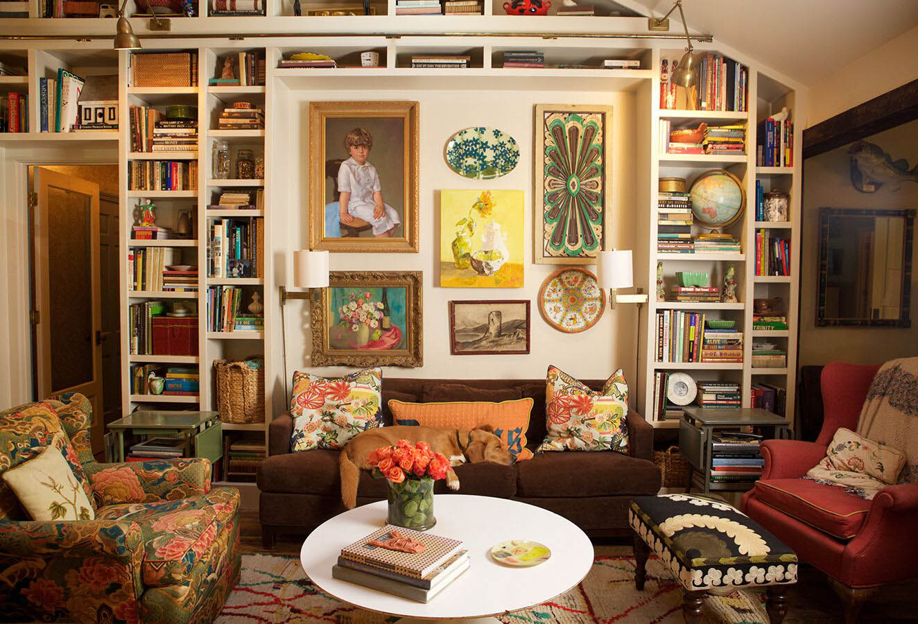 Living room with a gallery wall of painted portraits surrounded by bookshelves
